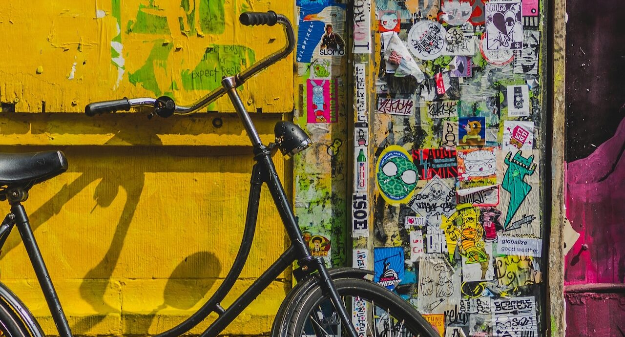 Bike parked beside wall full of stickers